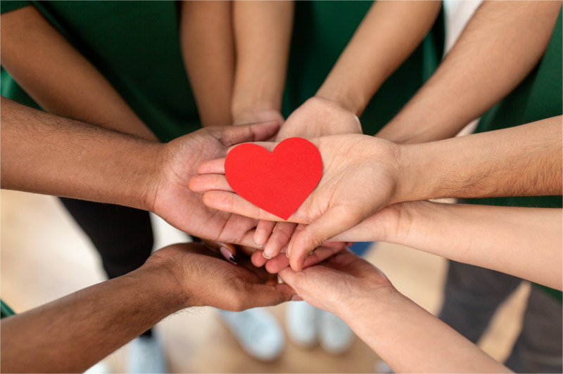A group of volunteers folded their hands, like a cheering gesture, with a heart on them.