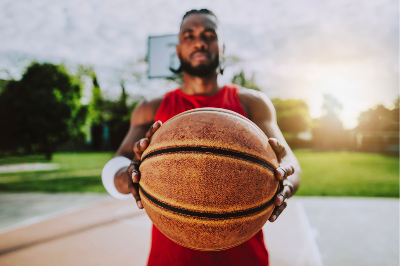 A basketball student-athlete holding a ball, representing their personal brand in the context of NIL (Name, Image, and Likeness) rights.