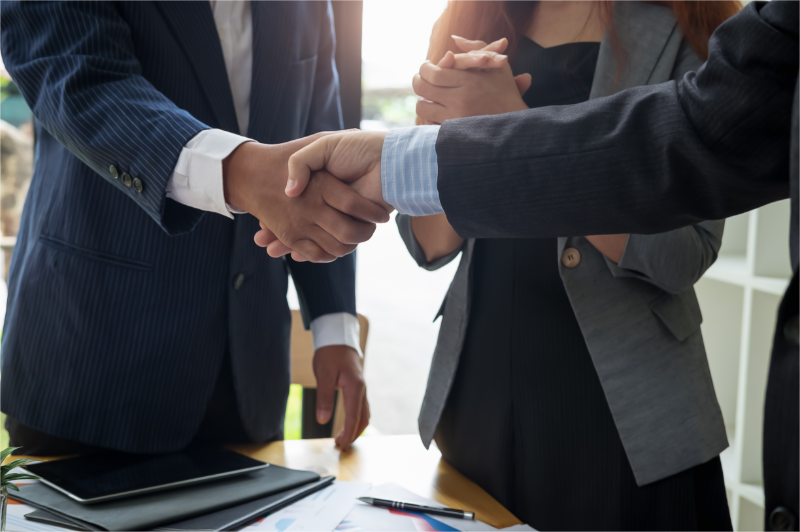 2 businessmen are shaking hands for their partnership.