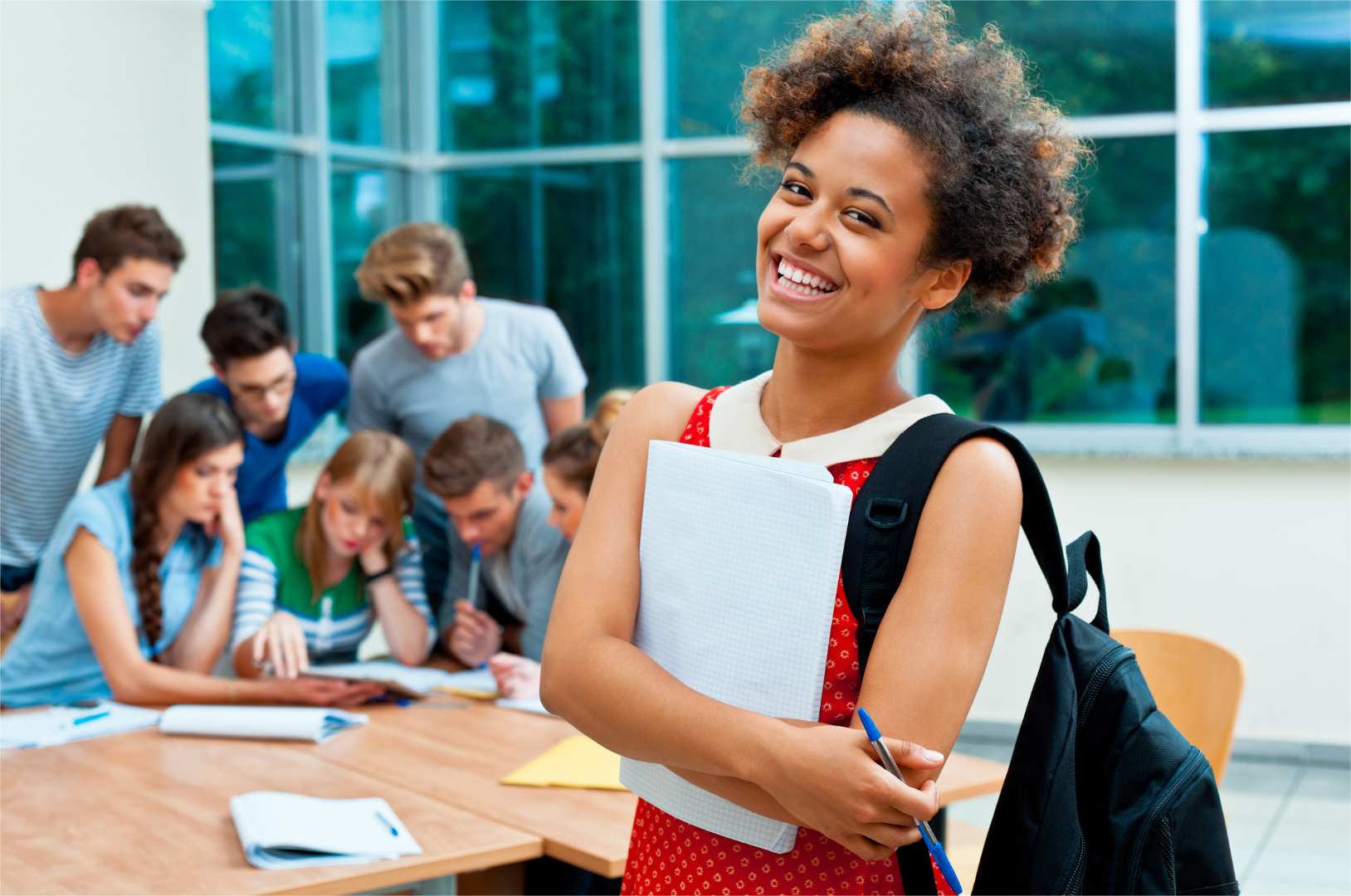 A happy college student in the front and a group of students in the background.